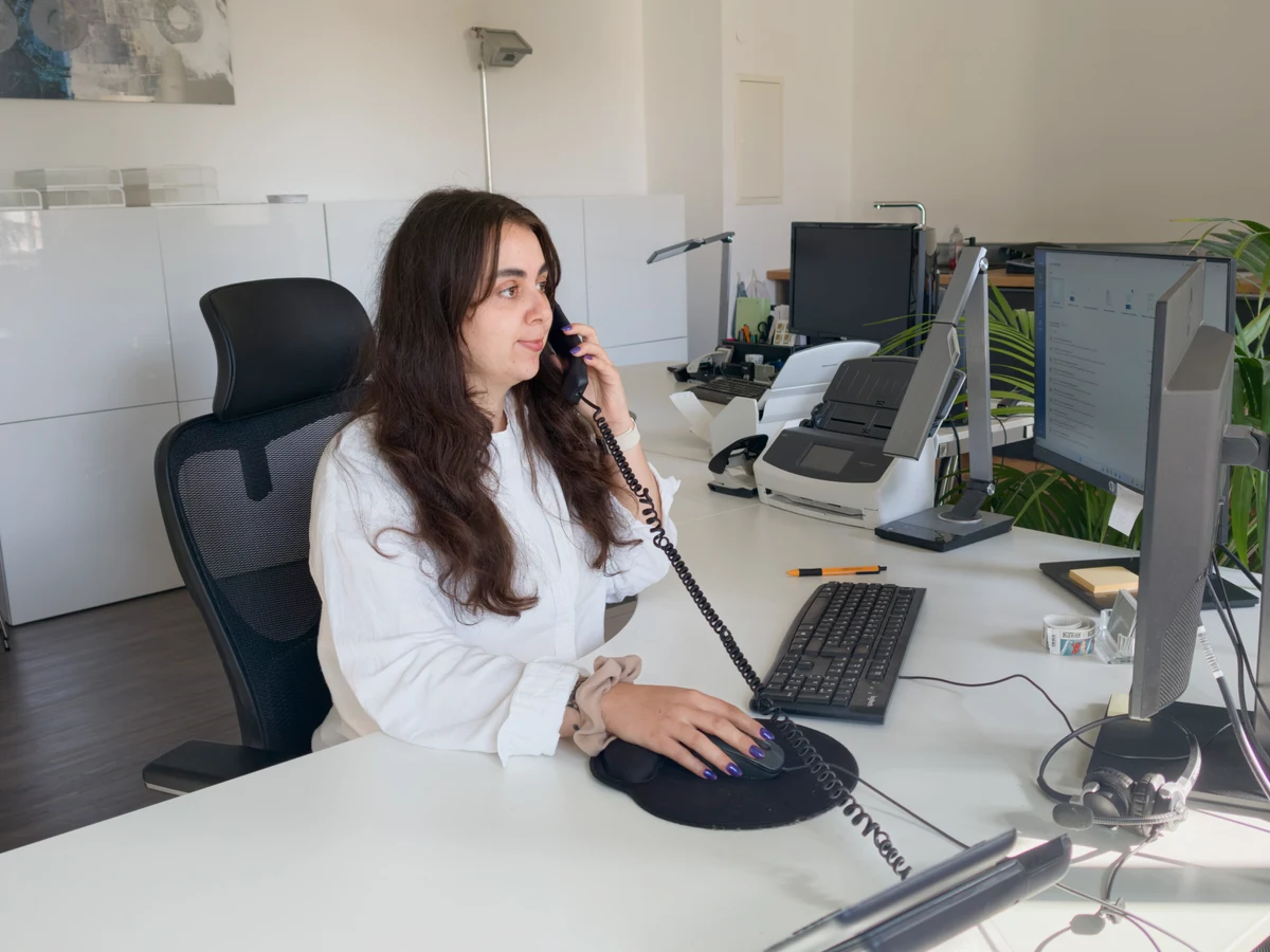 Mitarbeiterin telefoniert an ihrem Arbeitsplatz im Teambüro